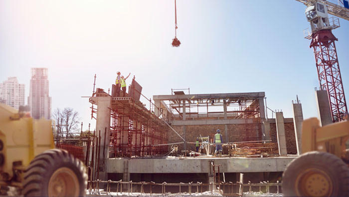 Crane over construction workers at sunny construction site