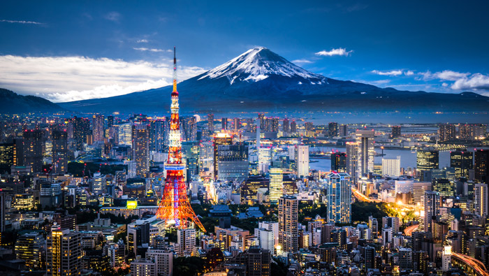 An early evening view of a Japanese city with Mount Fuji in the background.