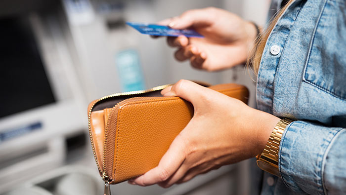 The hands of a woman holding a purse and a credit card