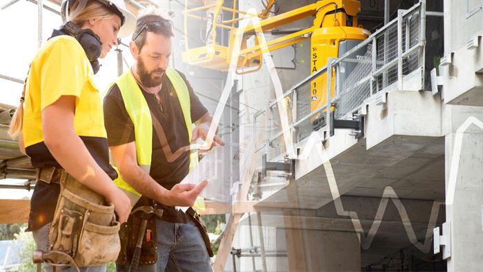 Two workers inspect a construction site, with a graph superimposed on the image.